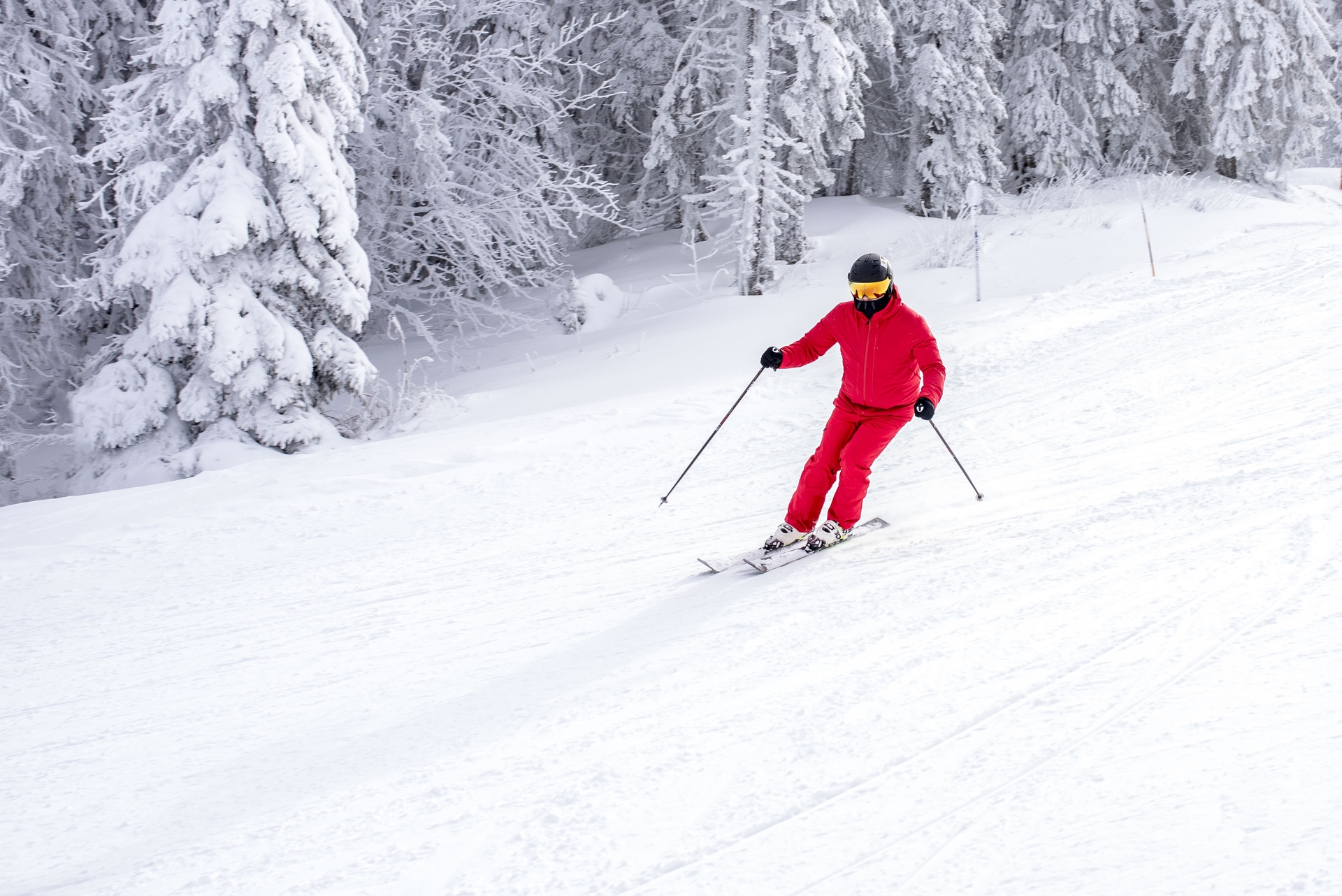 skier-ina-red-costume-skiing-down-slope-near-trees